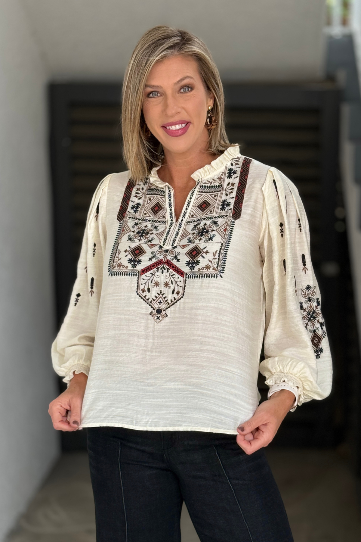 Side view of cream embroidered ruffle collar blouse with gathered sleeves