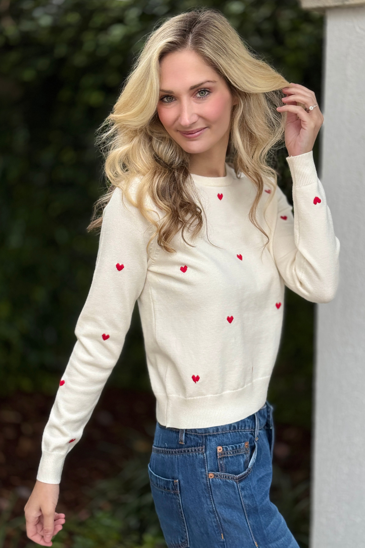 Women wearing heart embroidered sweater styled with jeans