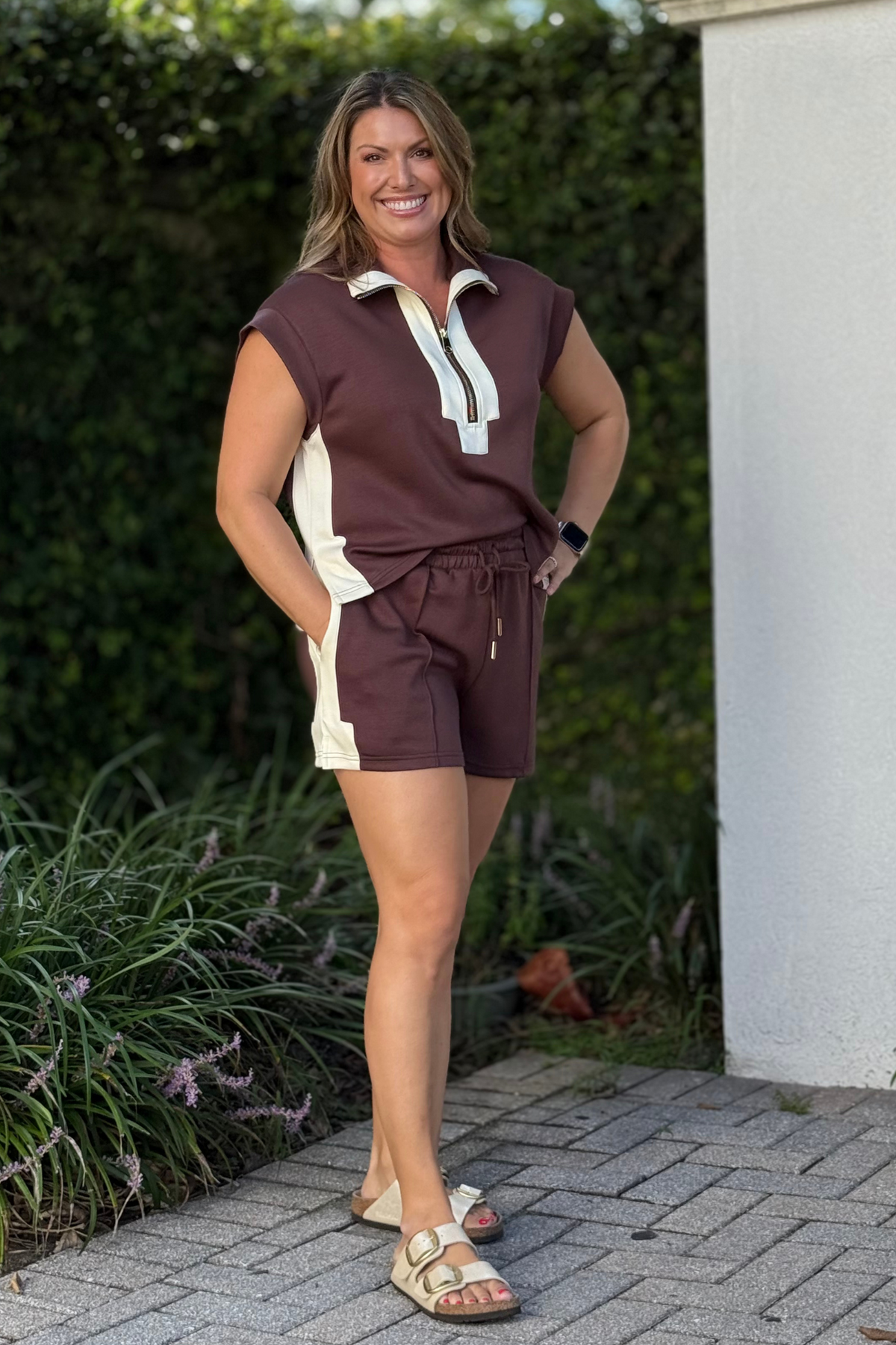 Woman wearing brown drawstring shorts with cream contrast side trim from The Pink Nickel Boutique.