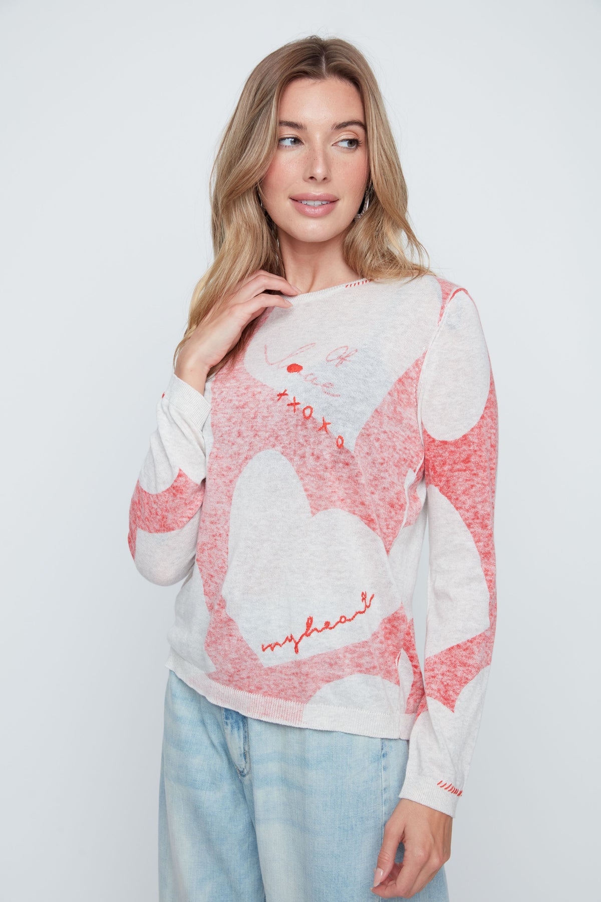 Woman wearing a pink and white patterned sweater with text on a plain background