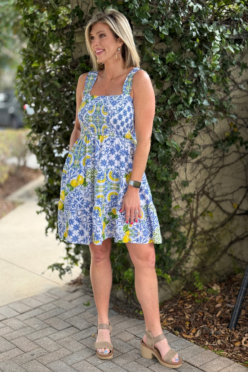 Shop the Alice Lemon Zest Sundress featuring a smocked bodice, tiered skirt, and playful lemon print perfect for summer days and vacation style.