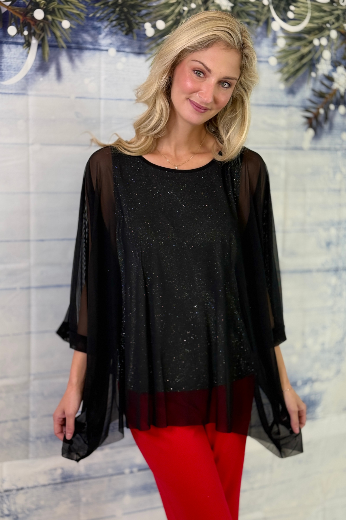 Women’s black shimmer tunic top styled with red pants