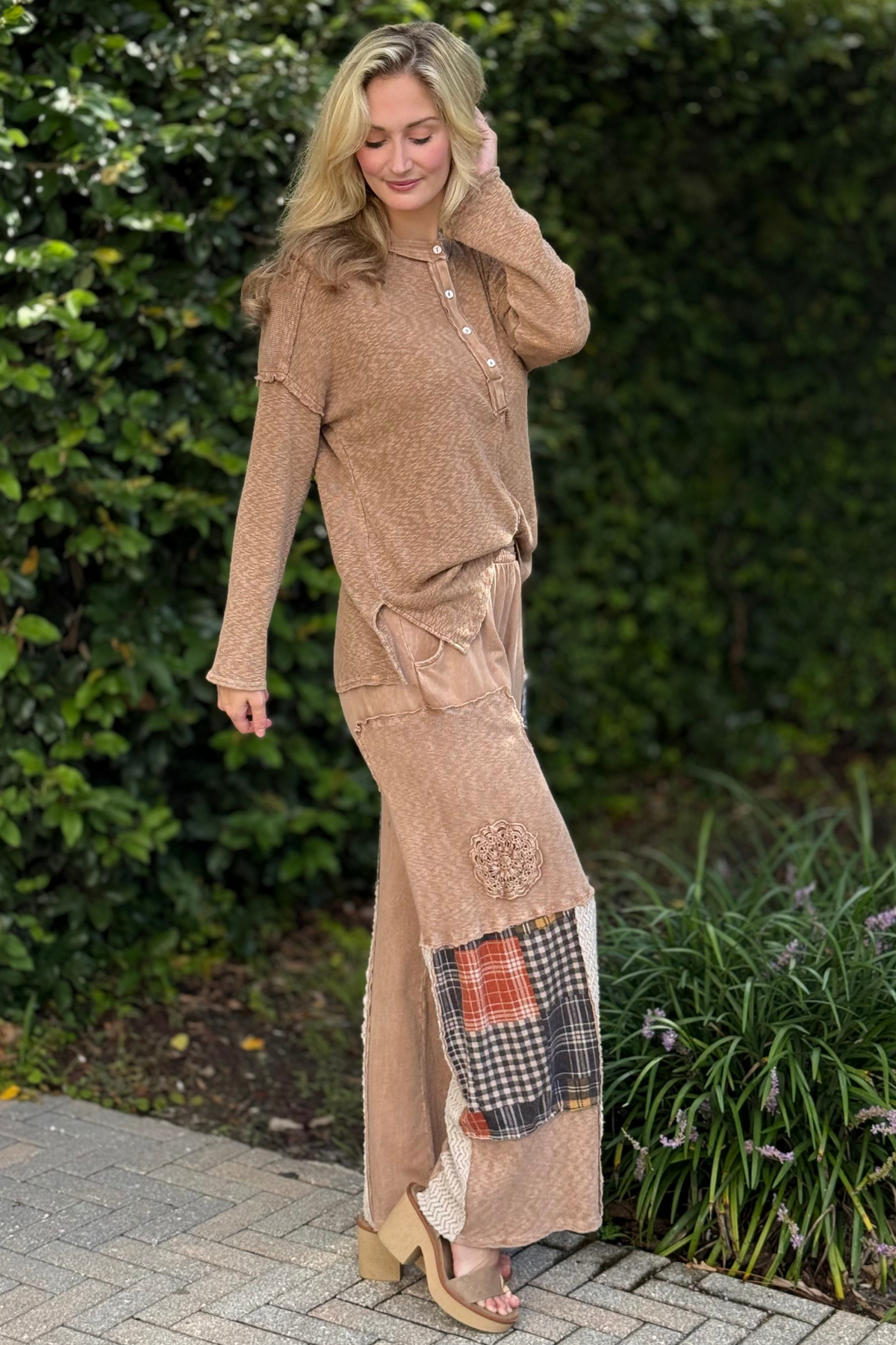 Woman wearing Patchwork Wanderer Pants – wide-leg boho pants with plaid patchwork and drawstring waist.
