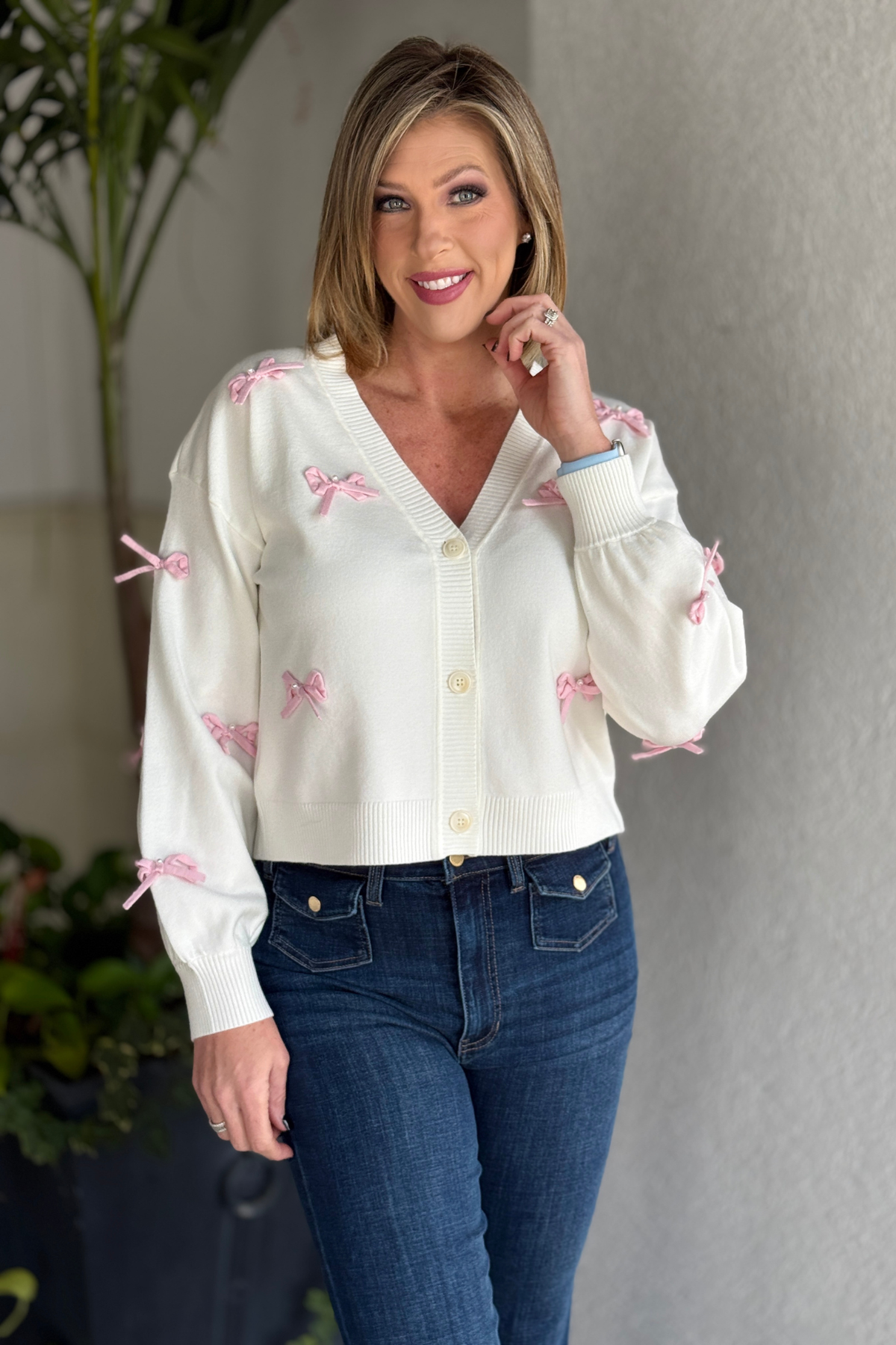 Soft white knit cardigan with delicate bow embroidery styled with jeans
