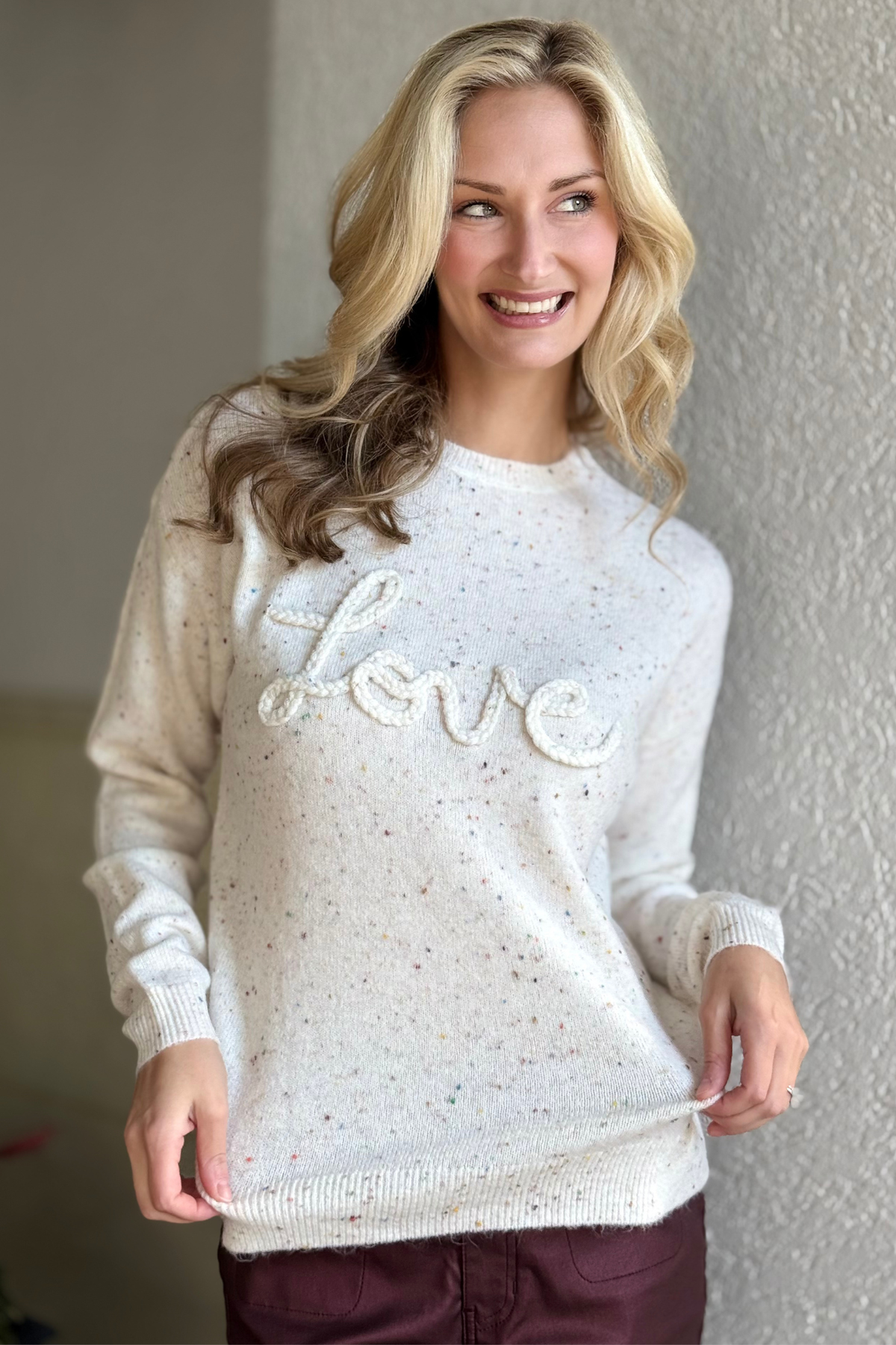 Close-up of braided “Love” embroidery and speckled knit texture on Charlie B Ecru Sweater.