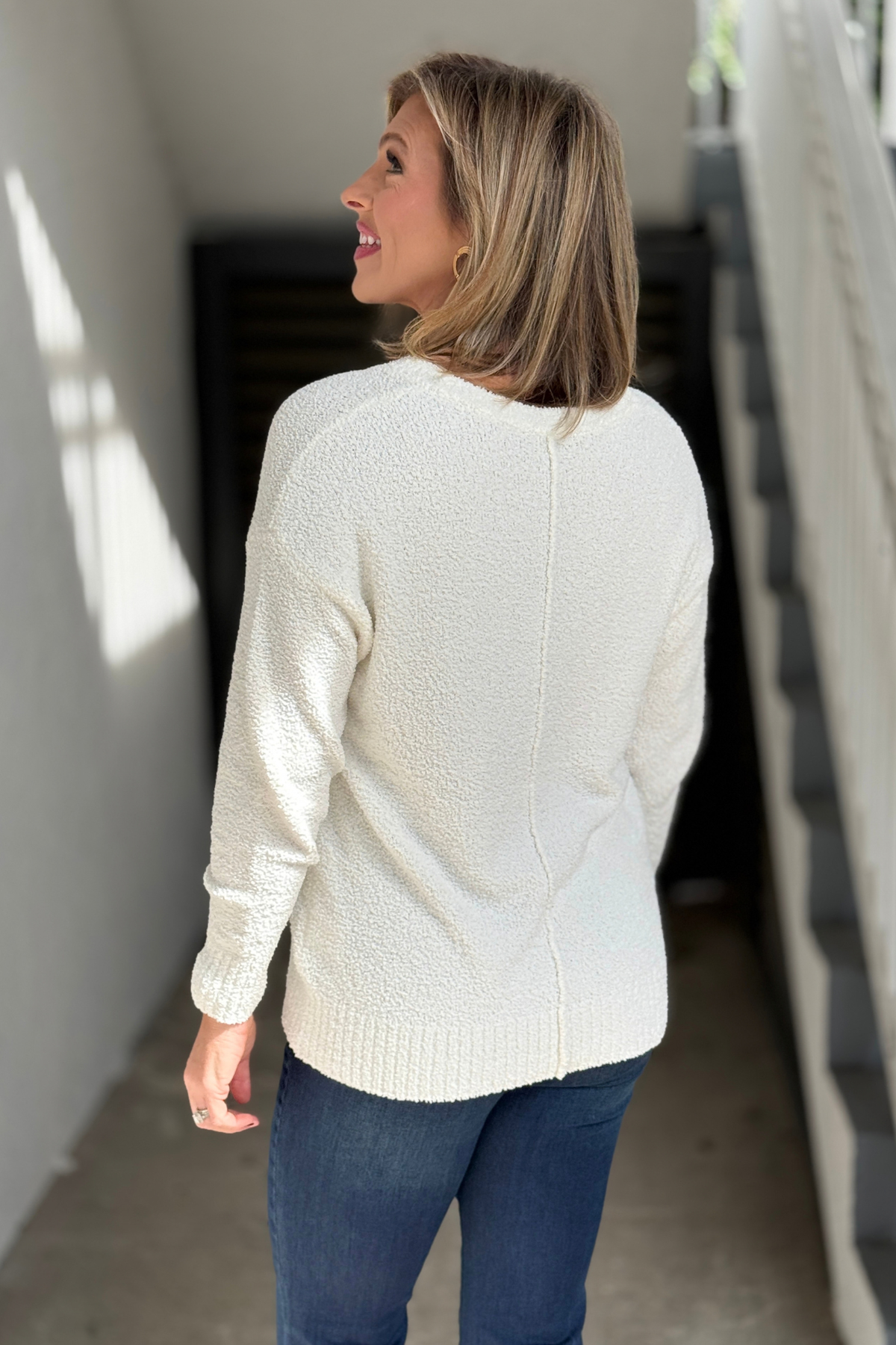 Ecru bouclé sweater styled with dark indigo jeans