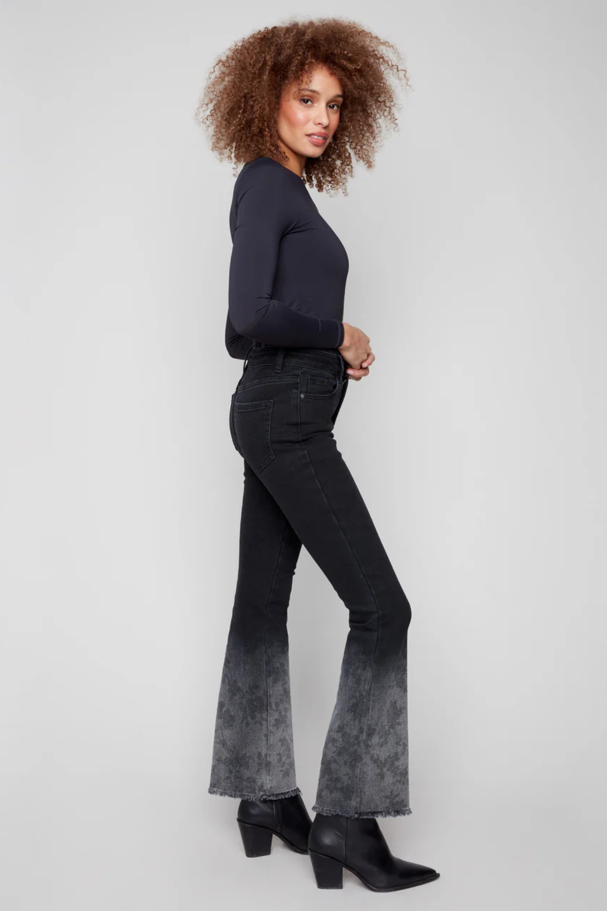 Woman wearing Charlie B Flared Jeans in charcoal with floral-washed frayed hem and flare leg design.