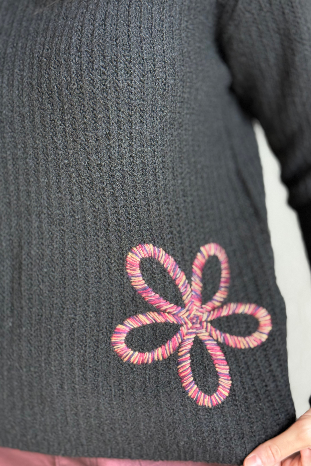 Close-up of floral soutache embroidery on sleeve and chest of Charlie B black sweater.