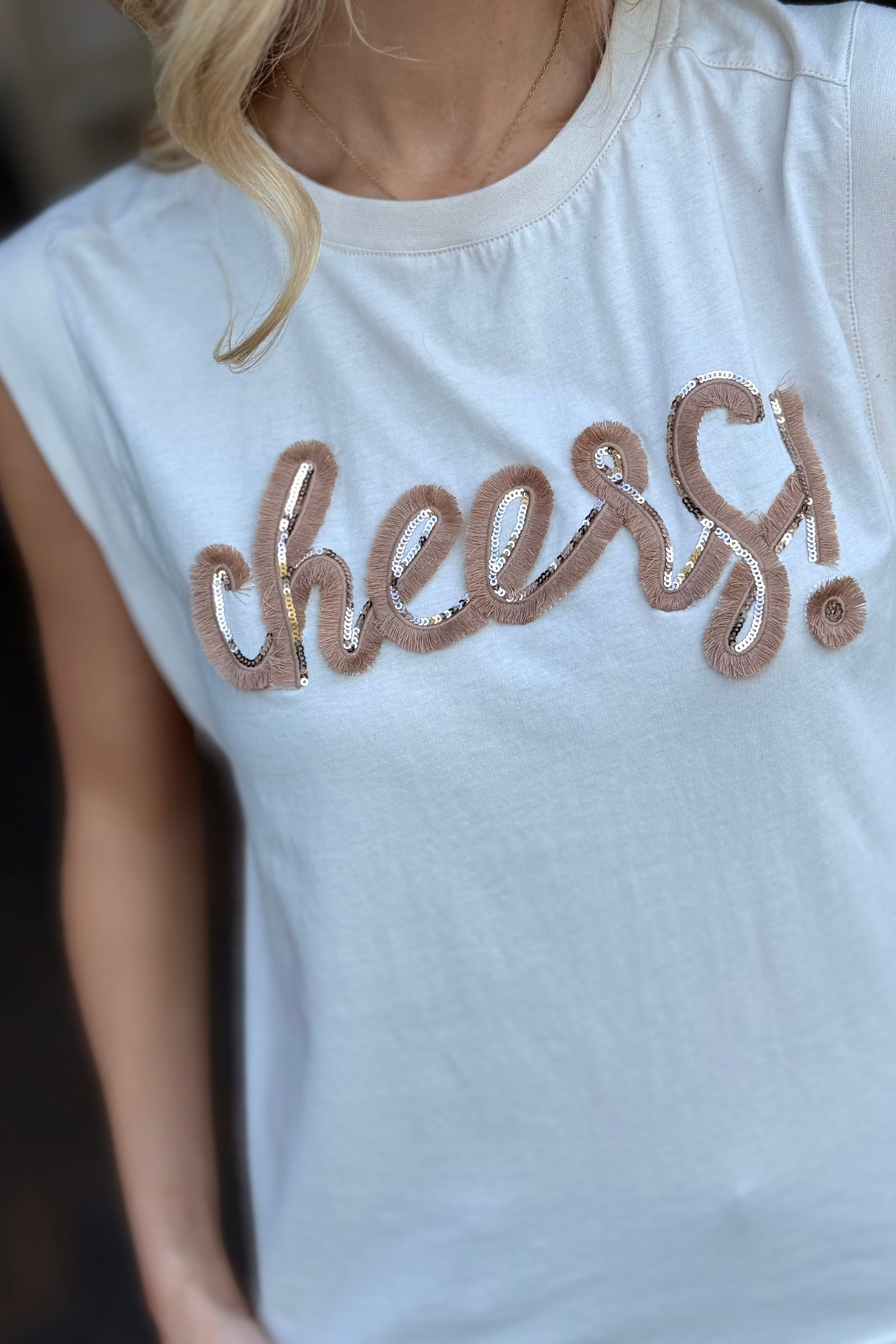 Close-up of sequin and textured embroidery on cheers graphic tank