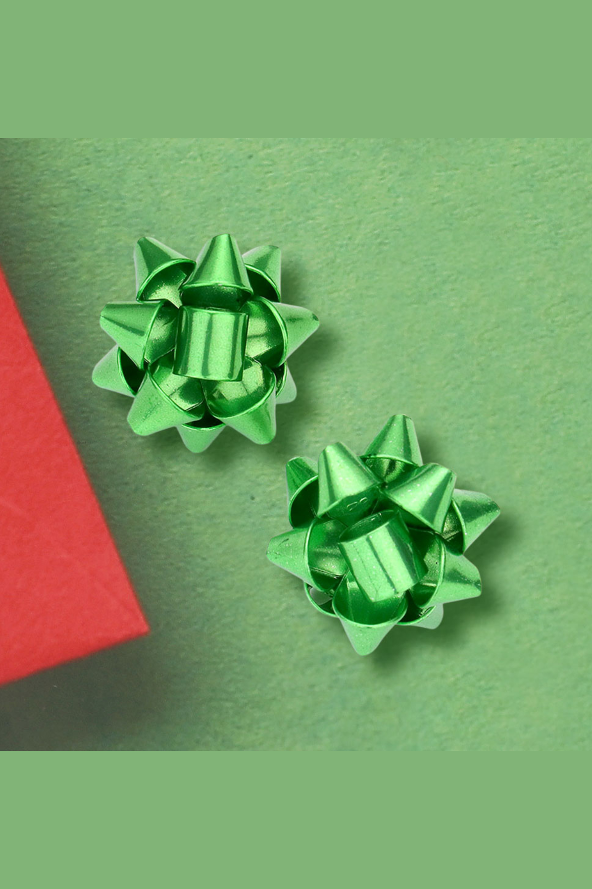 Green glimmer gift bow stud earrings displayed on a green background