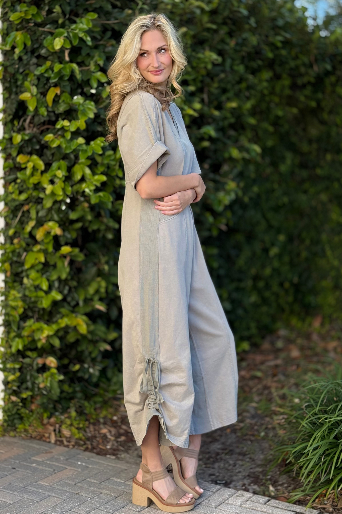Side view of olive utility jumpsuit with pockets