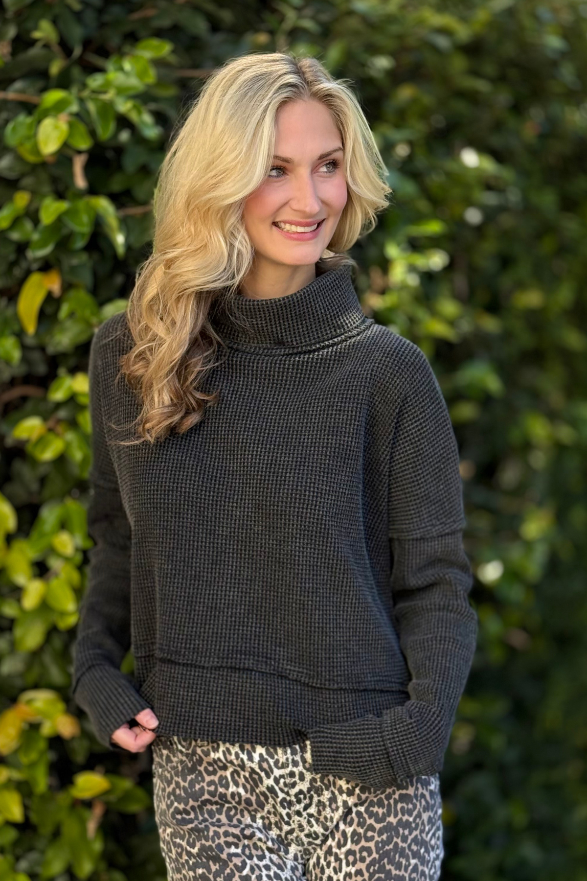 Side view of black waffle knit sweatshirt with side slits