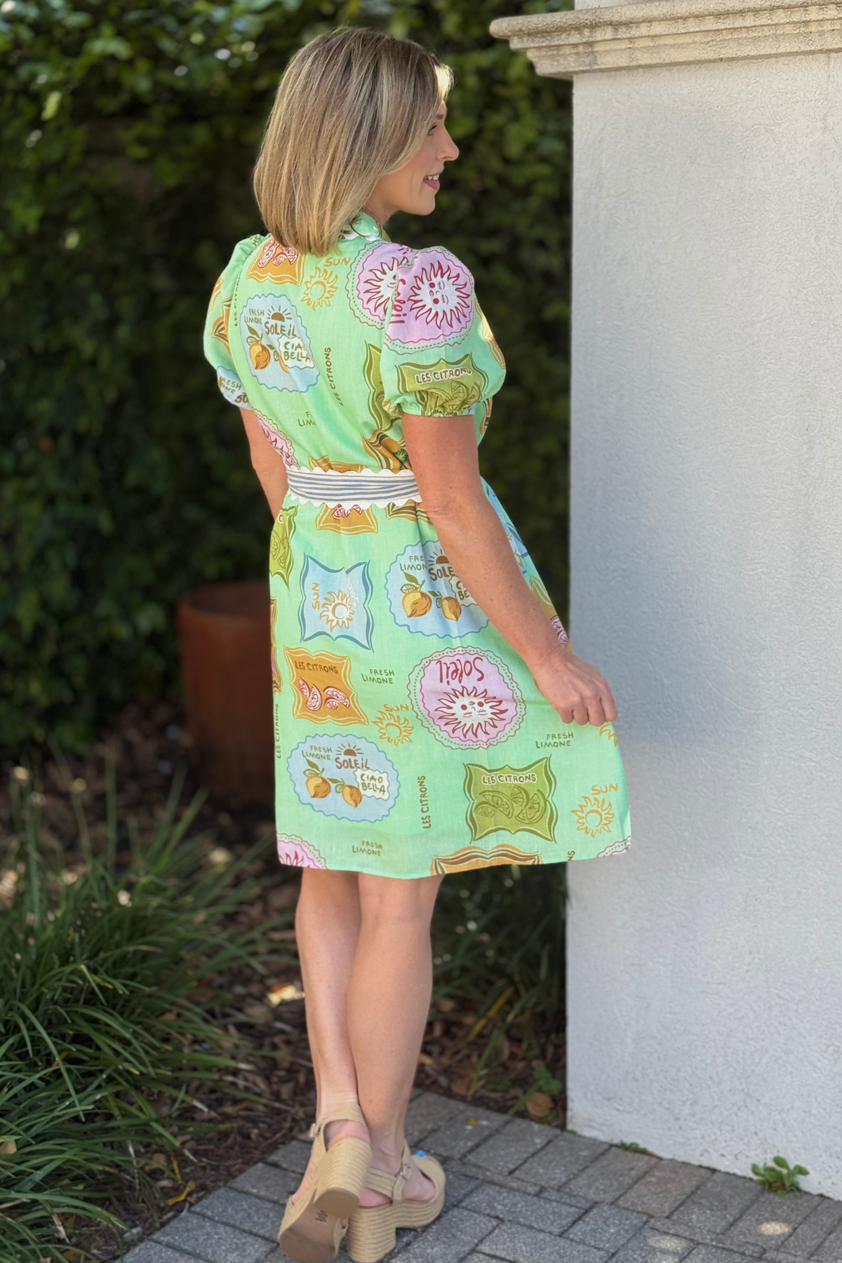 Side view of lightweight green printed dress with puff sleeves and belted waist