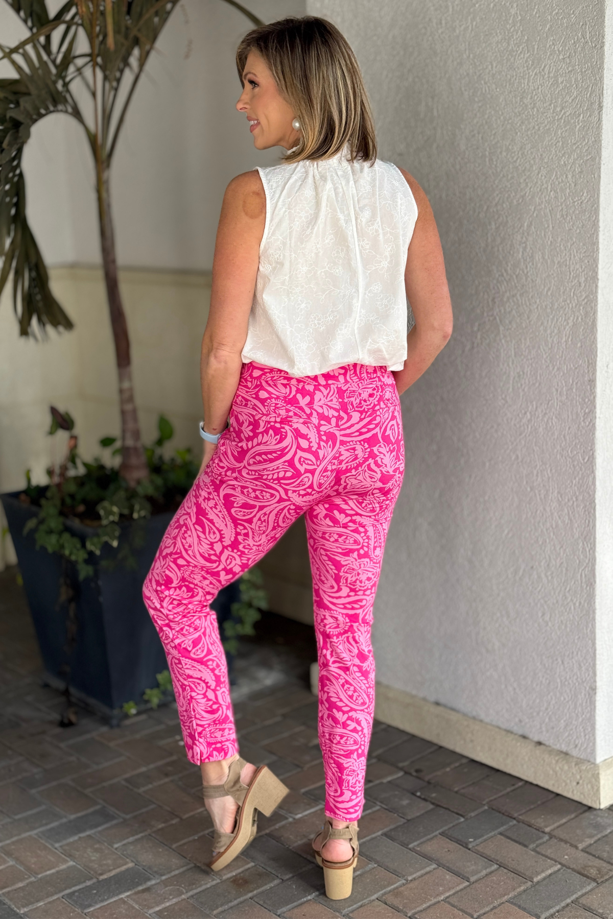 Woman wearing TPN hot pink paisley pants styled with white sleeveless blouse