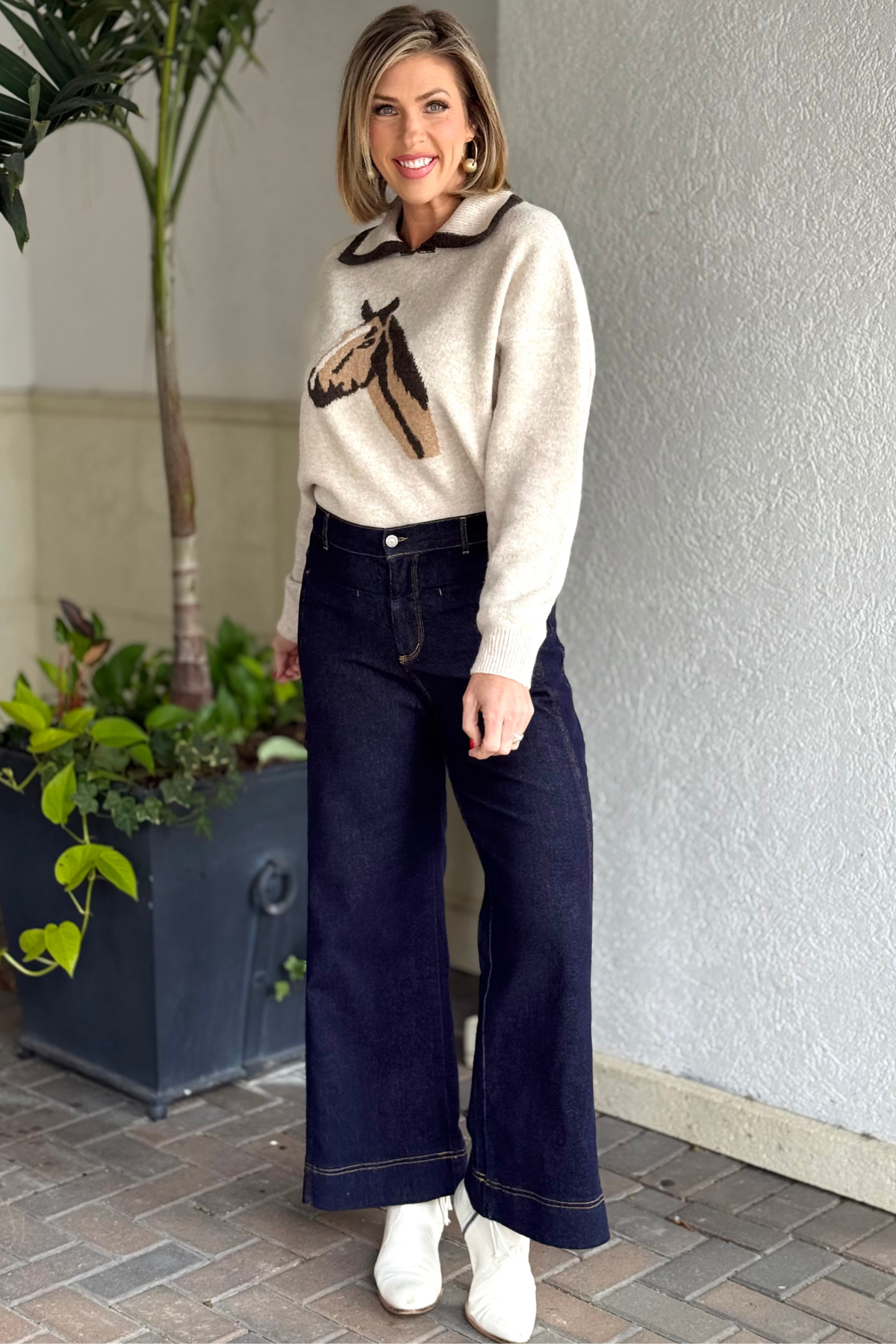 Model wearing dark wash wide-leg denim pants with contrast stitching