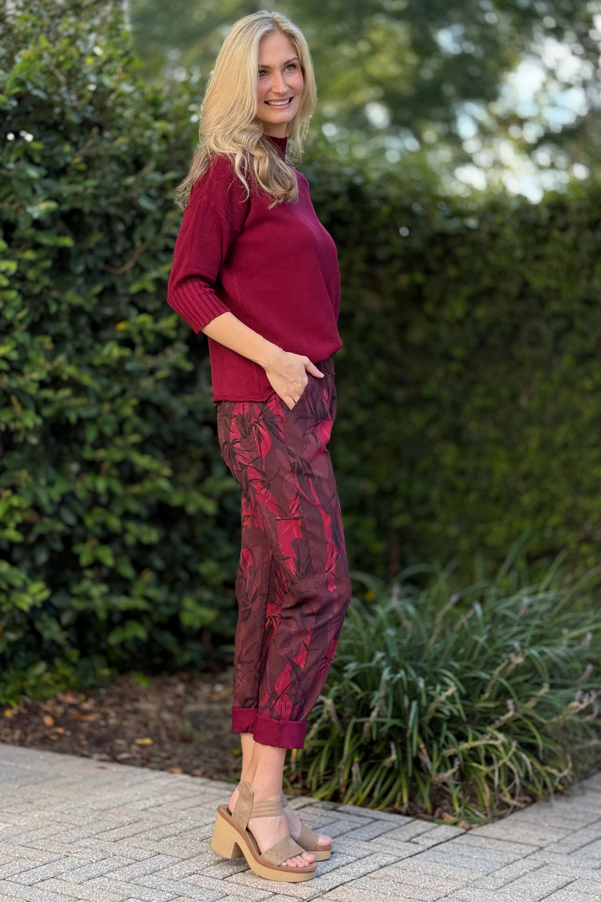 Lifestyle shot of Flora Ashley printed pants paired with burgundy mock neck sweater