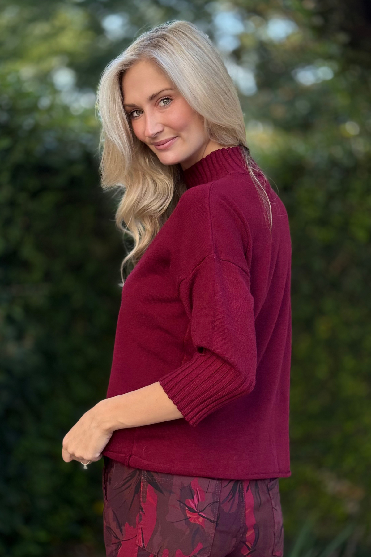 Lifestyle shot of Flora Ashley burgundy sweater paired with patterned trousers