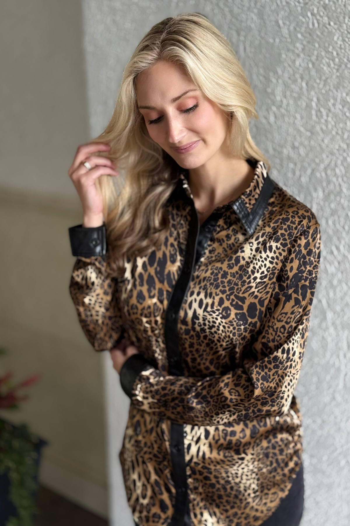 Frank Lyman Luxe Safari Blouse displayed on hanger — silky leopard print blouse with faux leather trim and button-down front.