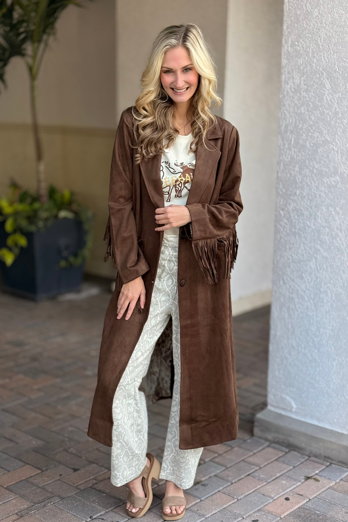 Model wearing The Saddleback Suede Fringe Coat in brown