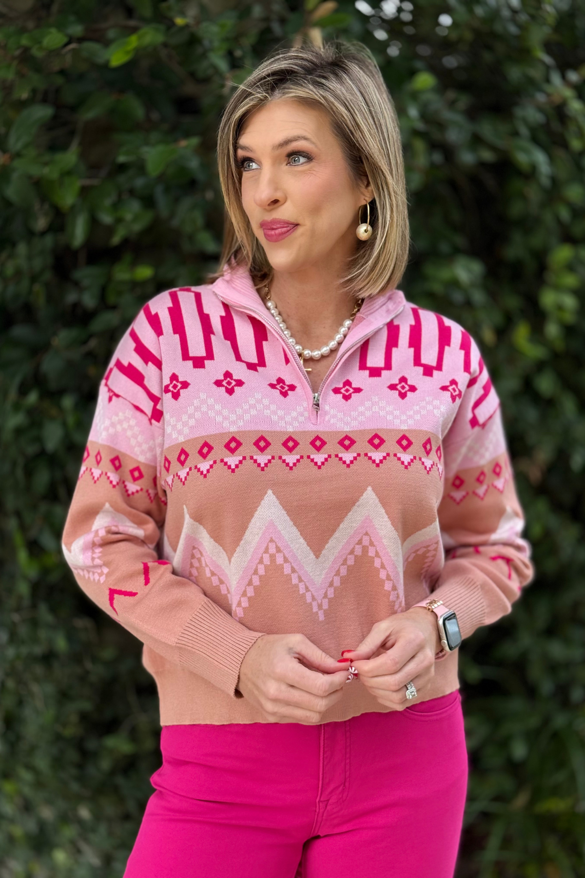 Woman wearing pink geometric half zip mock neck sweater outdoors