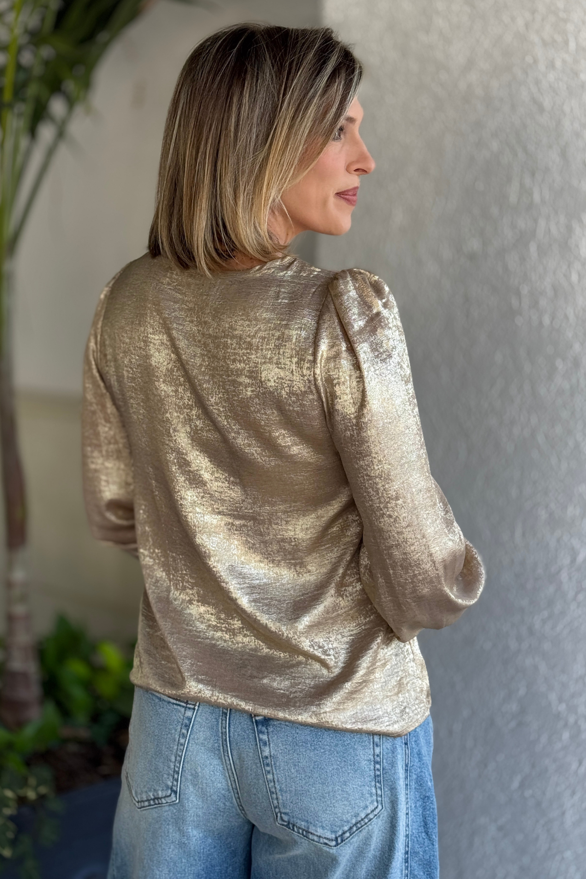 Model smiling in metallic gold blouse from The Pink Nickel
