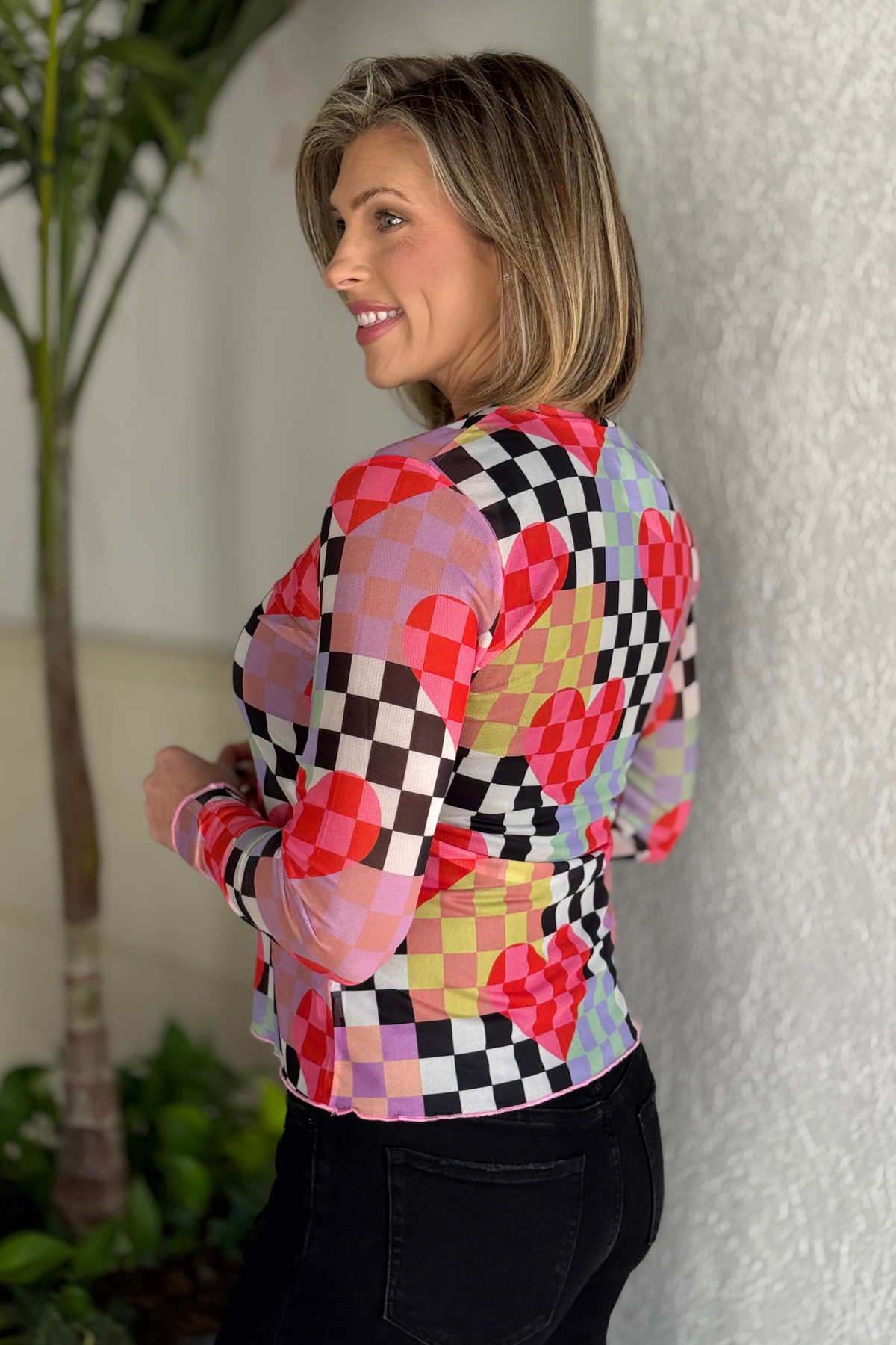 side angle of boutique checkered heart mesh shirt styled with black jeans