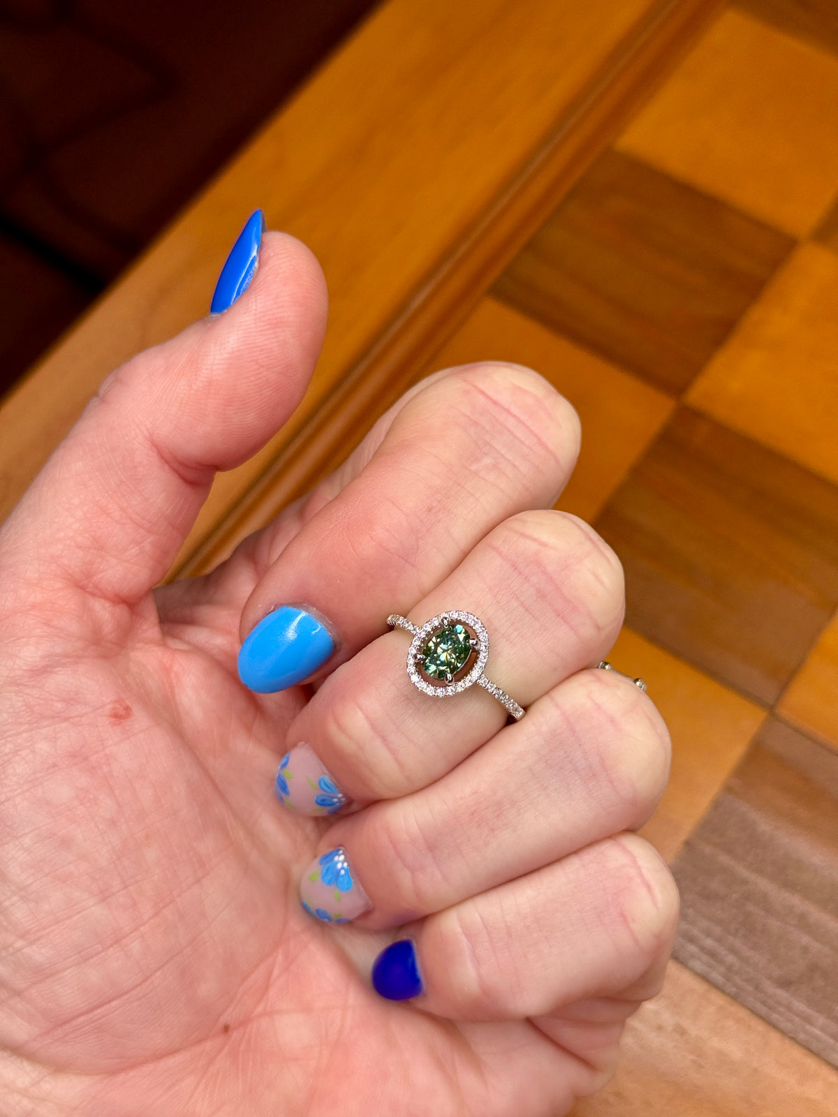colored moissanite halo ring with green sparkle on hand
