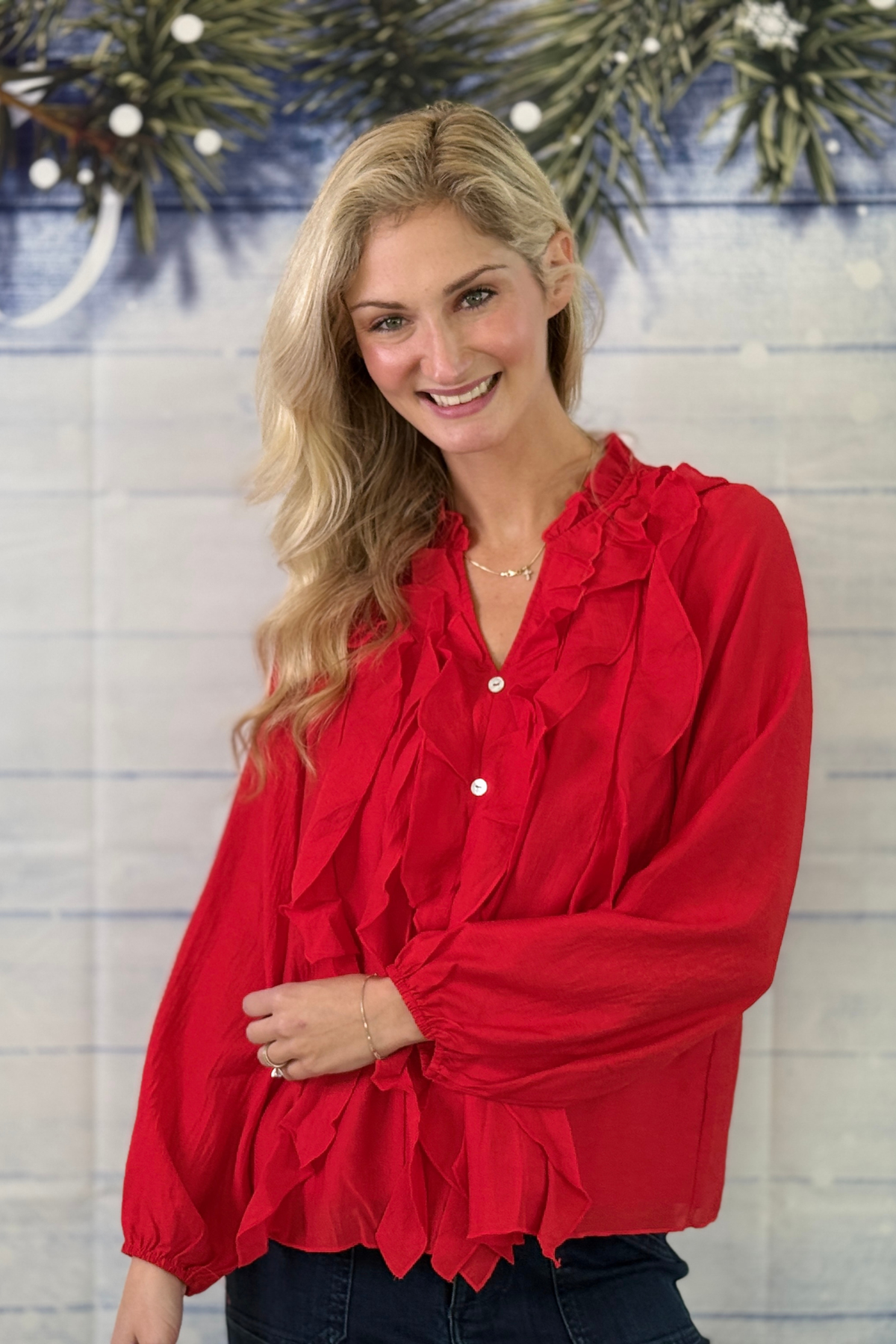 Women's holiday red ruffle blouse styled with dark denim