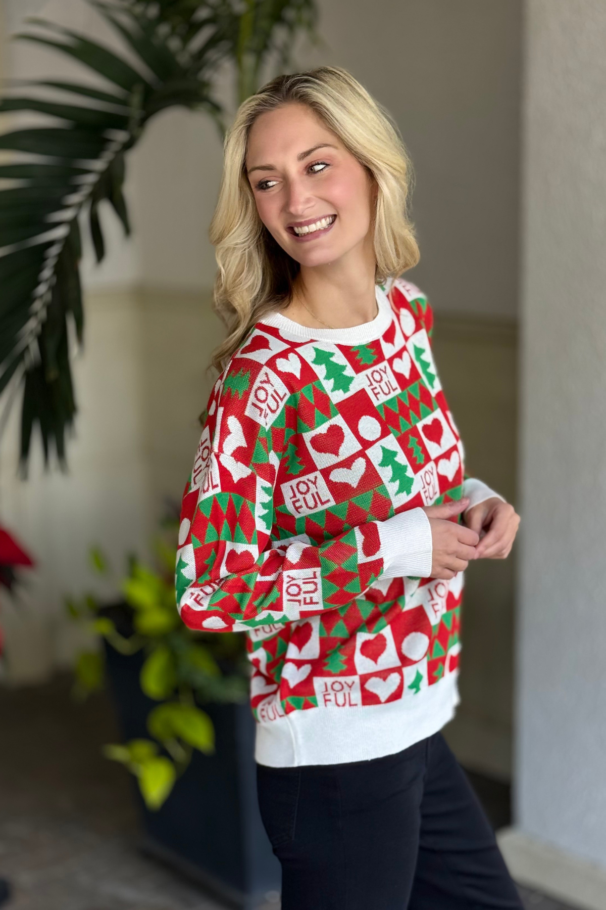 Joyful graphic Christmas sweater with red and green icons on a white trim.