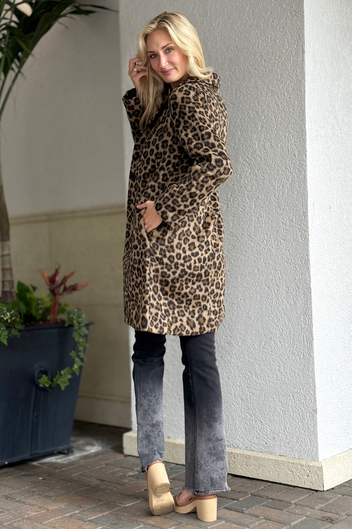 Model wearing The Camden Leopard Coat, a long leopard print coat with notch lapel and single-button closure.