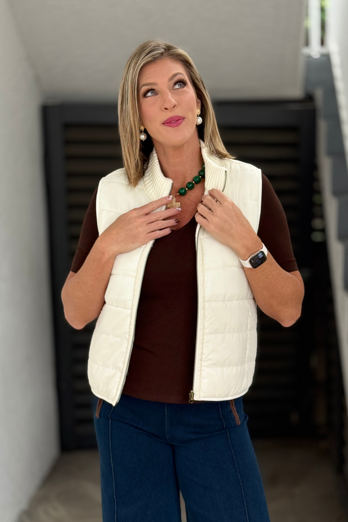 Women’s cream reversible quilted vest styled with denim trousers