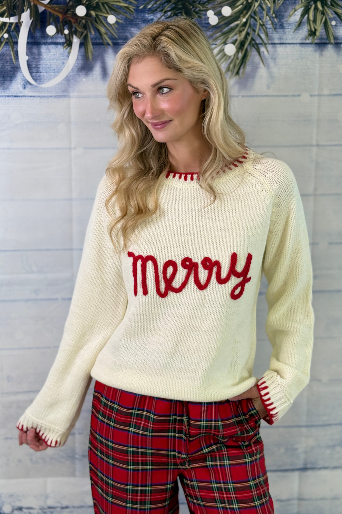 Women’s festive holiday sweater paired with red plaid pants  