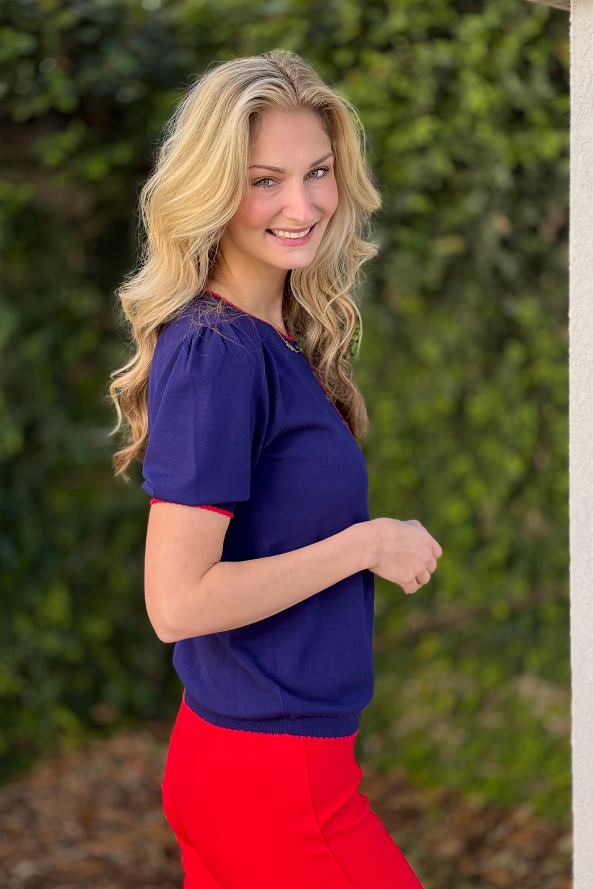 Navy puff sleeve contrast sweater styled with bold red bottoms