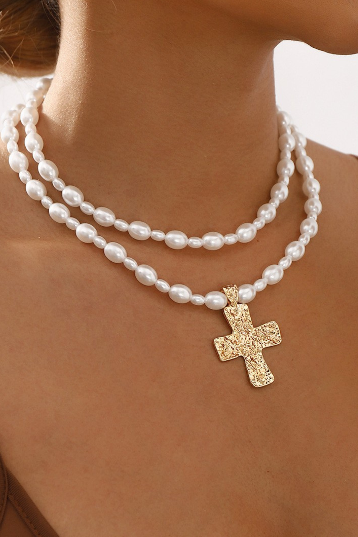 layered pearl necklace with gold cross pendant close up