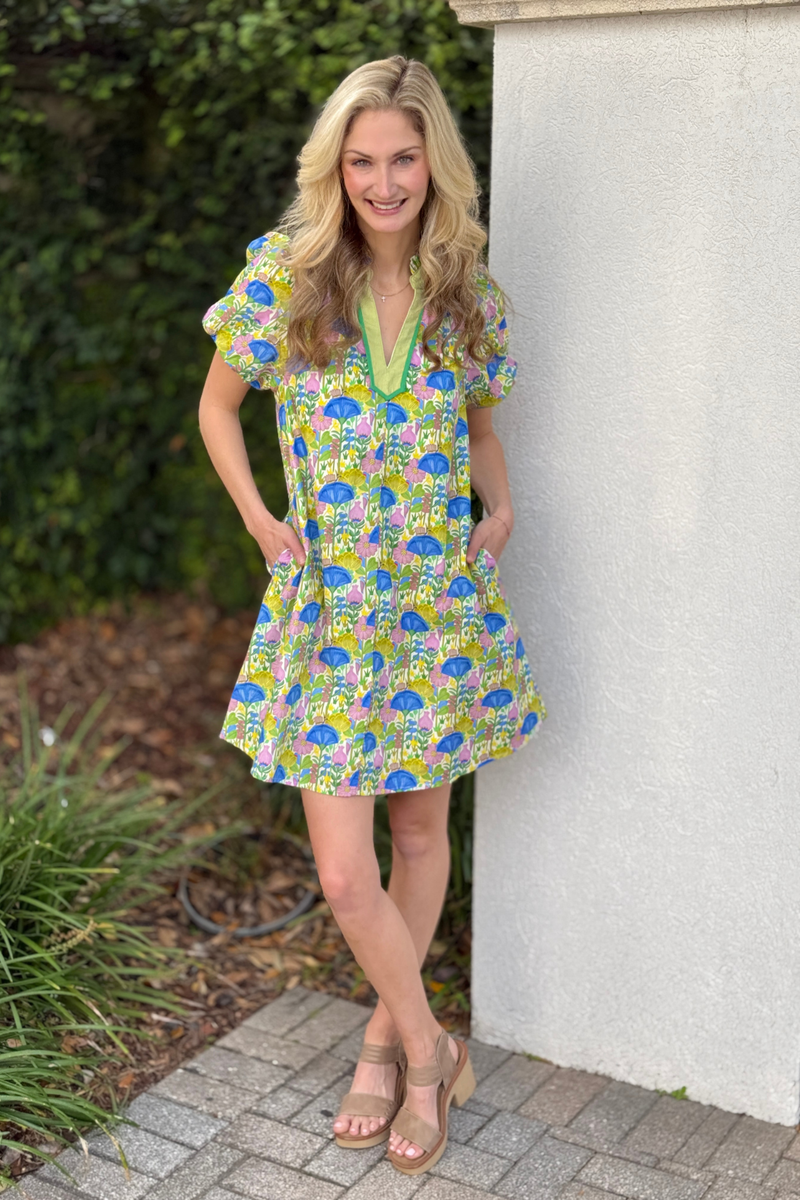 Woman wearing colorful printed notch neck dress with lace trim and ruffled collar