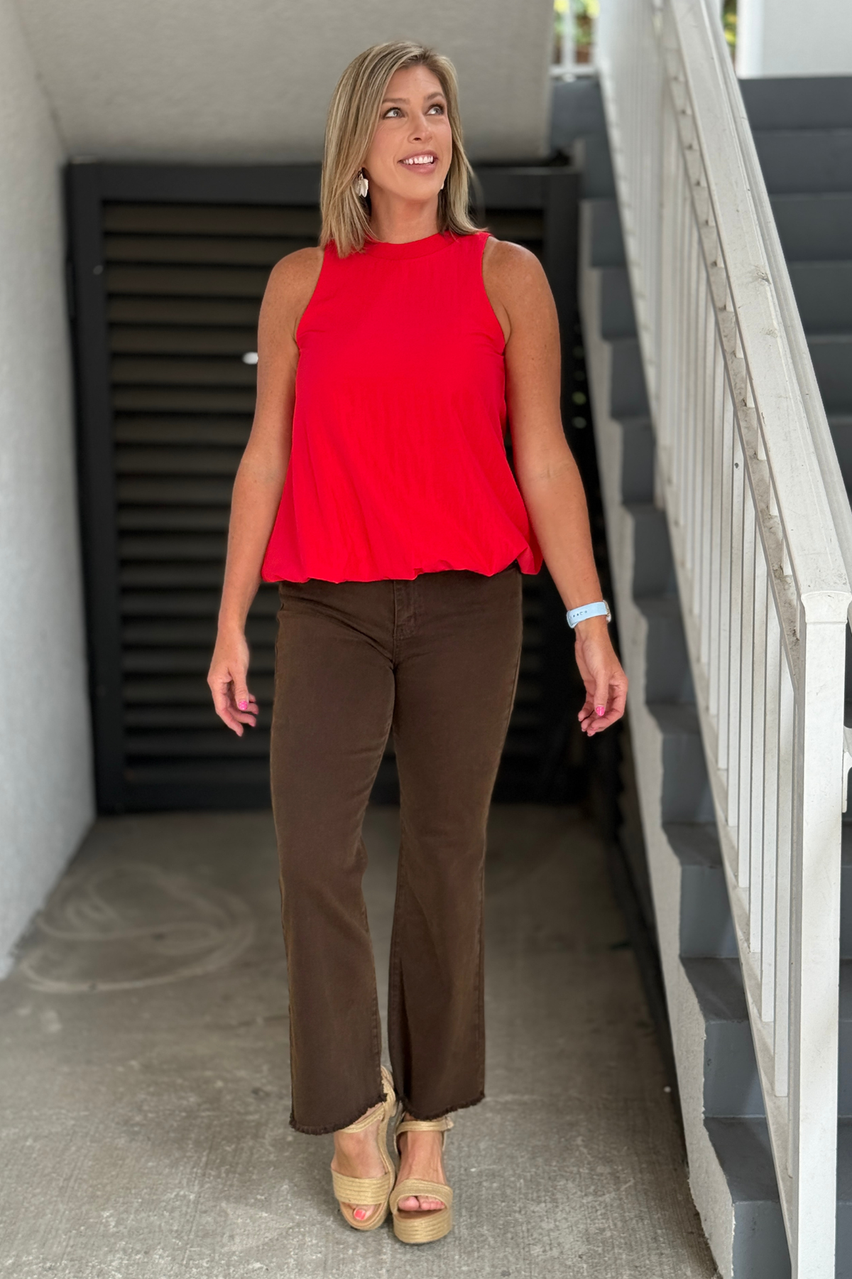 Red mock neck bubble hem top styled with brown pants.
