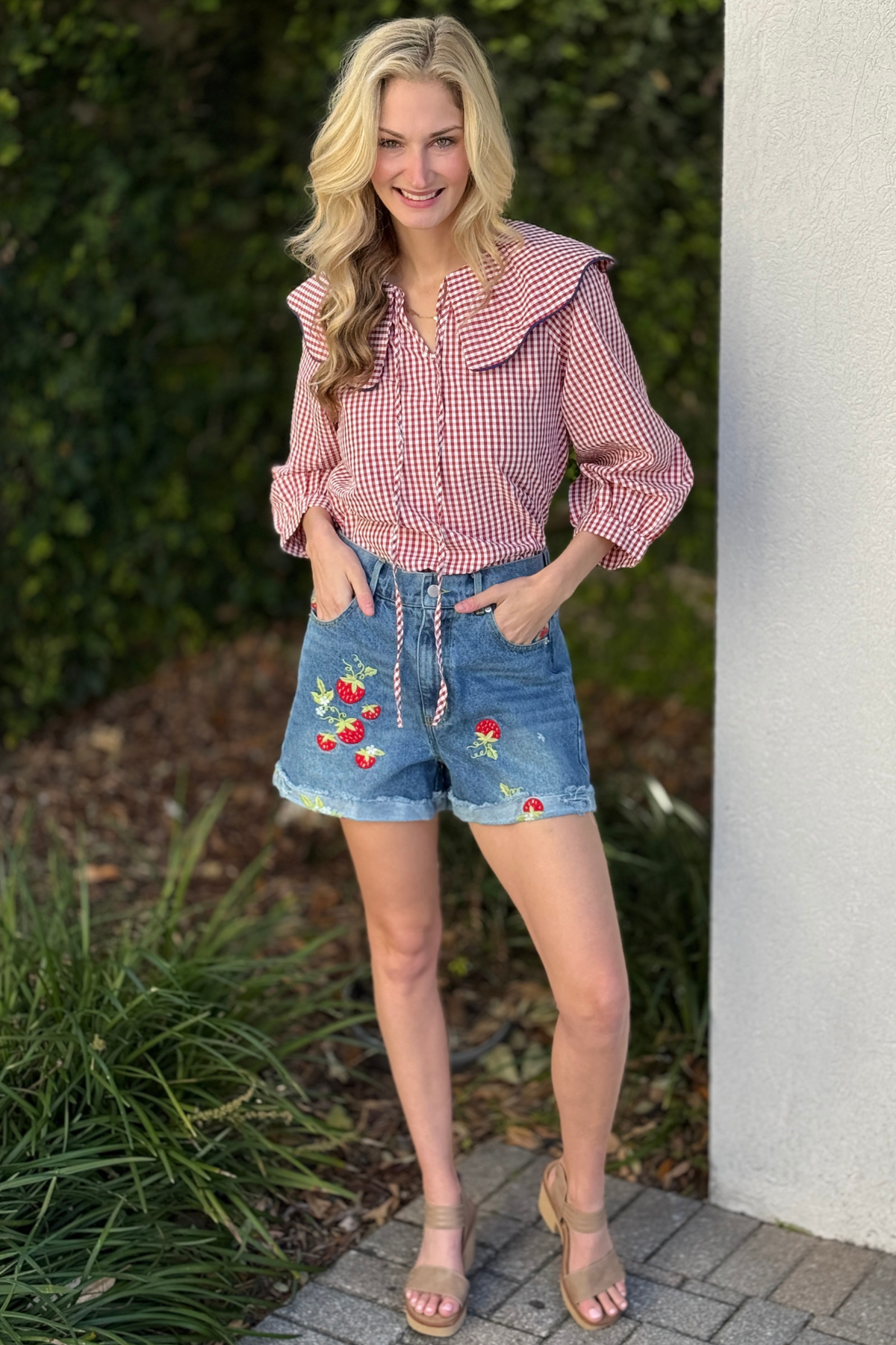 Close up of strawberry embroidery on washed denim shorts