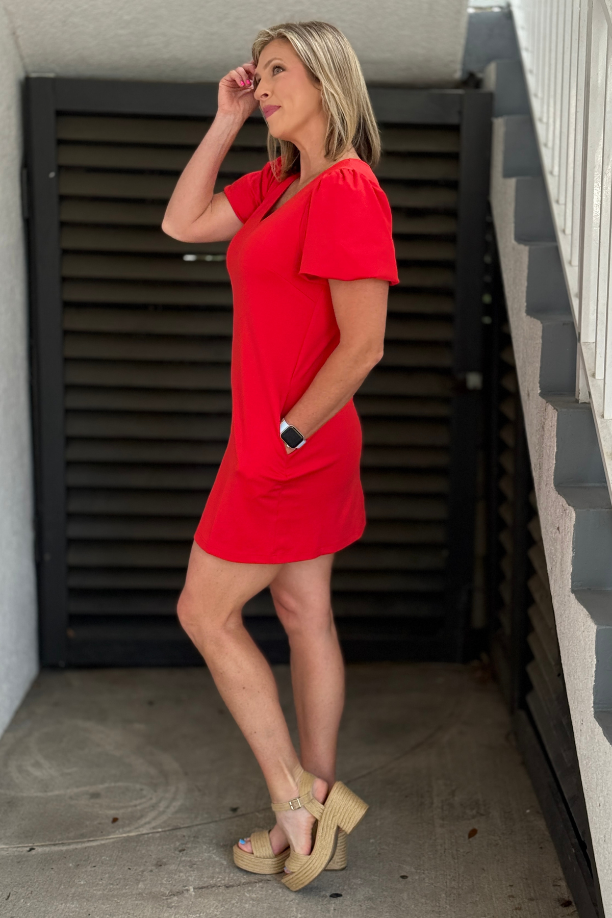 Woman wearing a bright red shift dress with puff sleeves