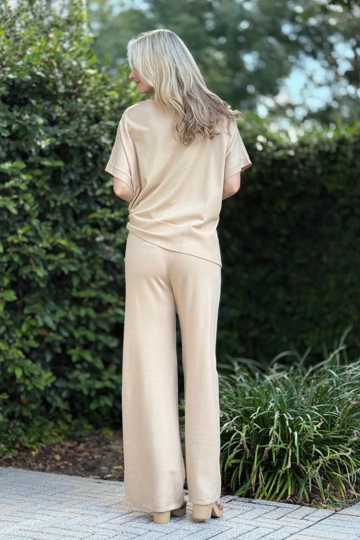Lifestyle shot of Renuar Knit Pull-On Flare Pants paired with matching tan poncho top