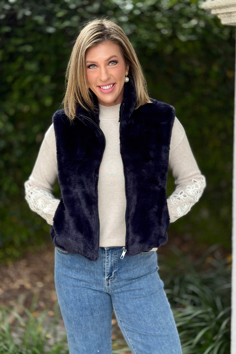 Women’s navy faux fur vest layered over neutral sweater