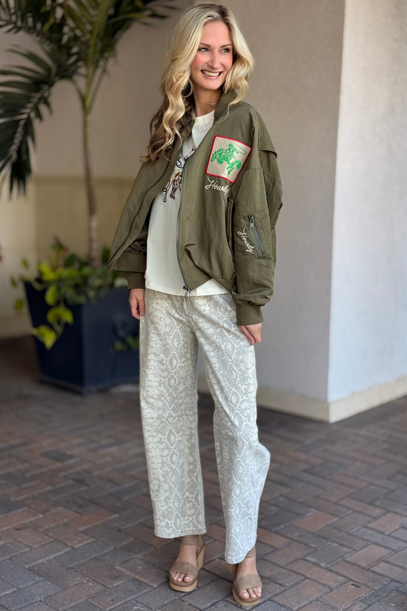 Model wearing olive embroidered rodeo bomber jacket layered over graphic tee
