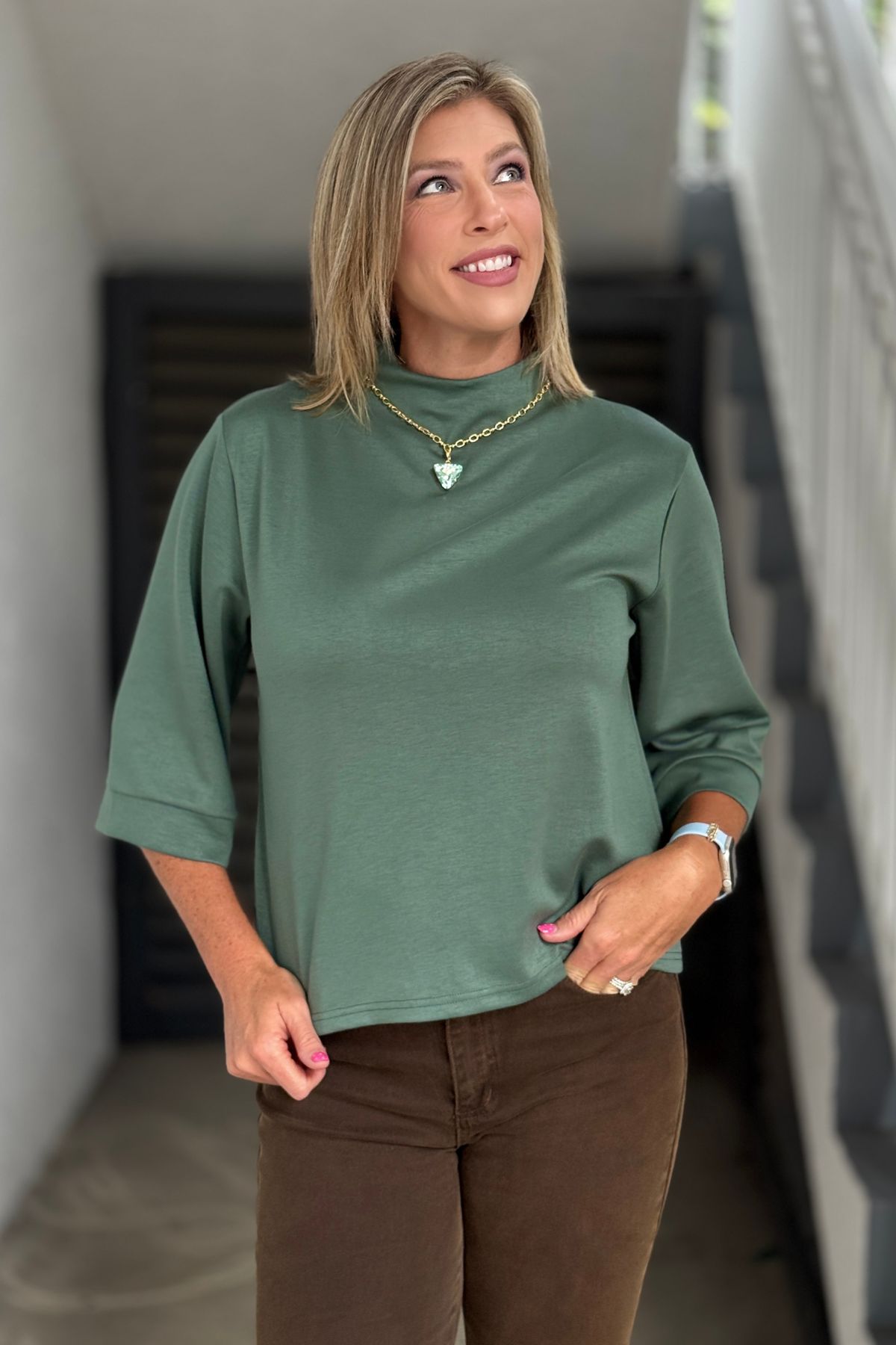 Woman wearing the Everyday Luxe 3/4 Sleeve Mock Neck Knit Top in slate green with espresso wide leg jeans for a polished fall outfit.