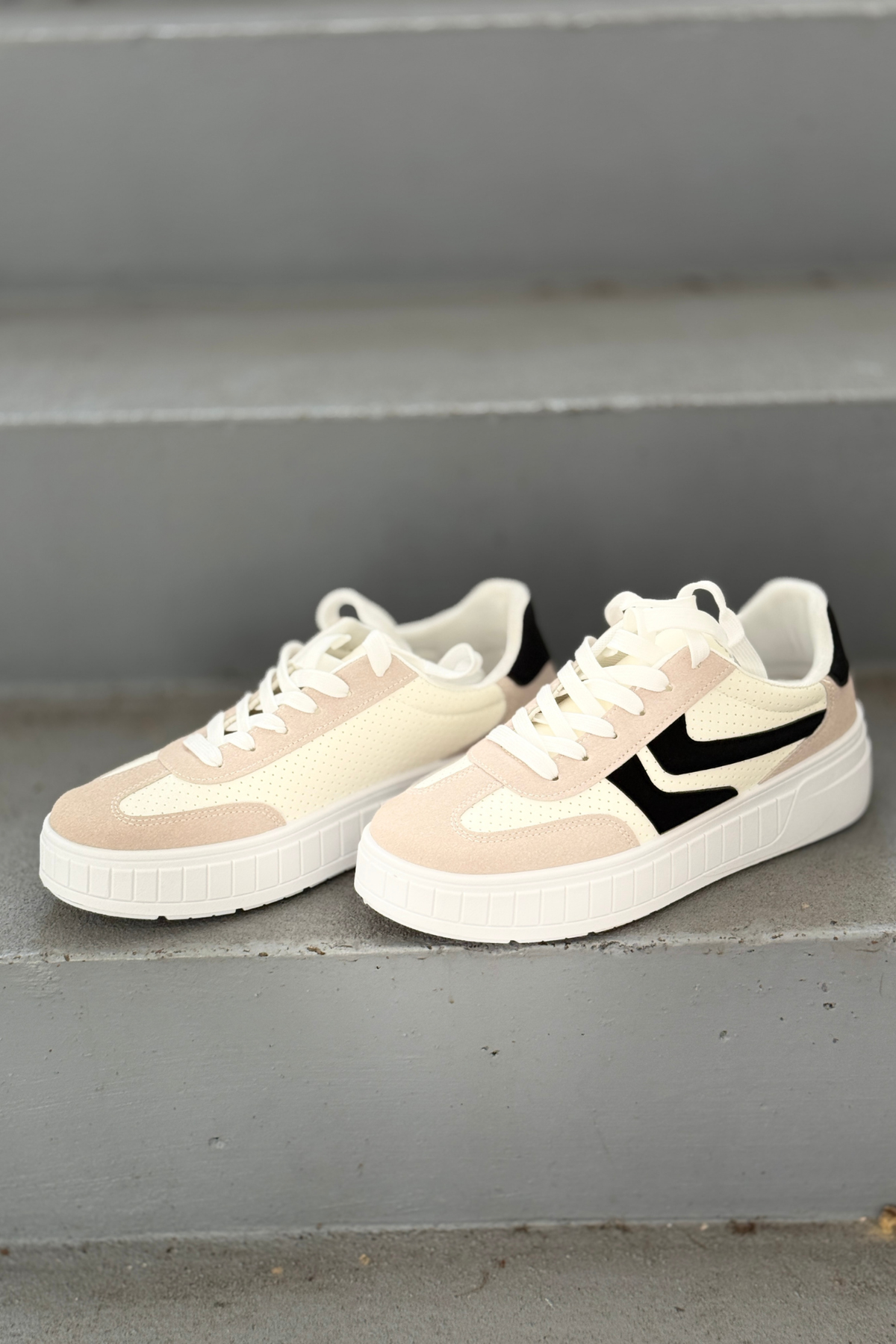 Side view of ivory platform sneakers featuring black contrast detail and lightweight sole.