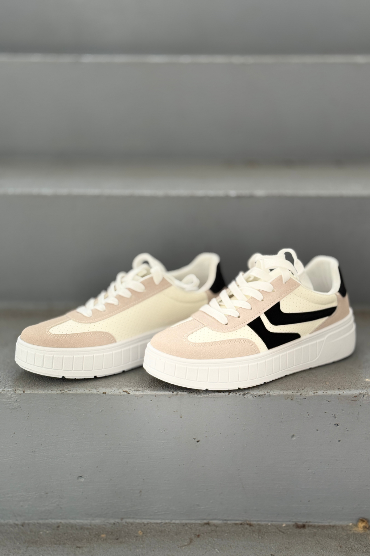Women's ivory and black platform fashion sneakers with lace-up design and cushioned white sole.