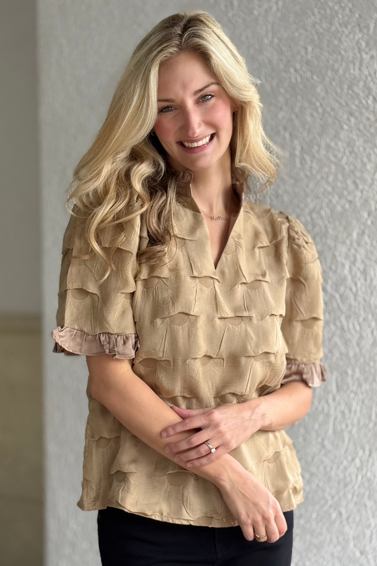Woman wearing a beige ruffled blouse against a plain background