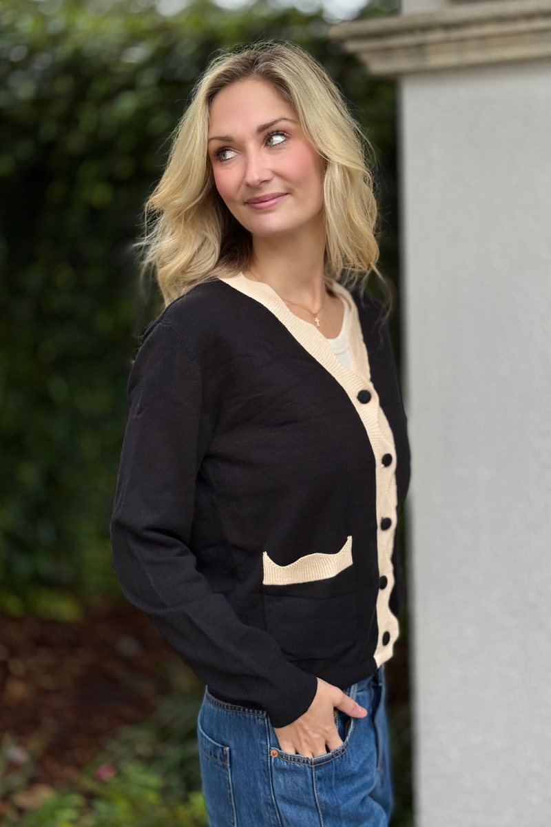 Scalloped pocket detail on black cardigan sweater
