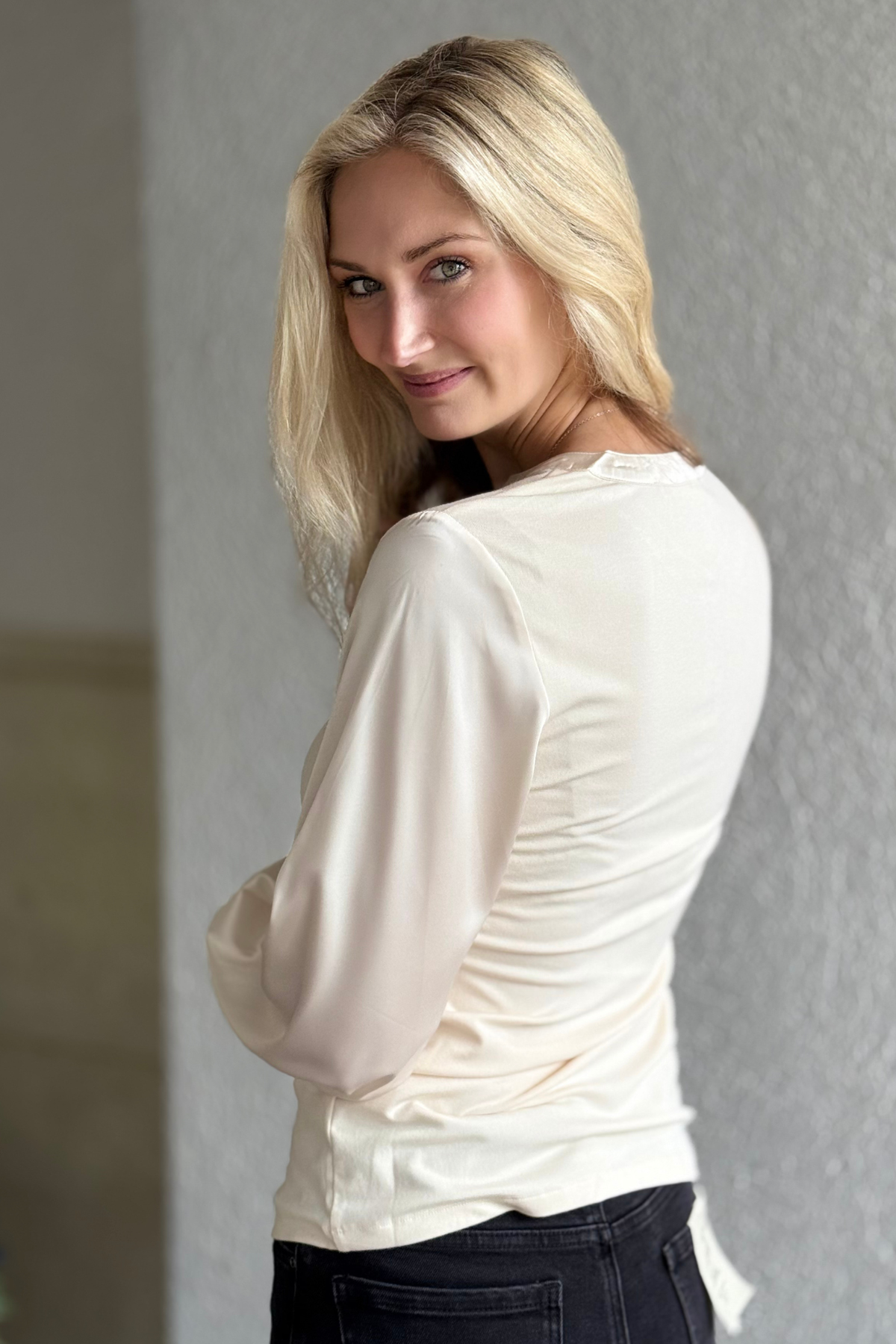 Woman wearing a white blouse against a plain background