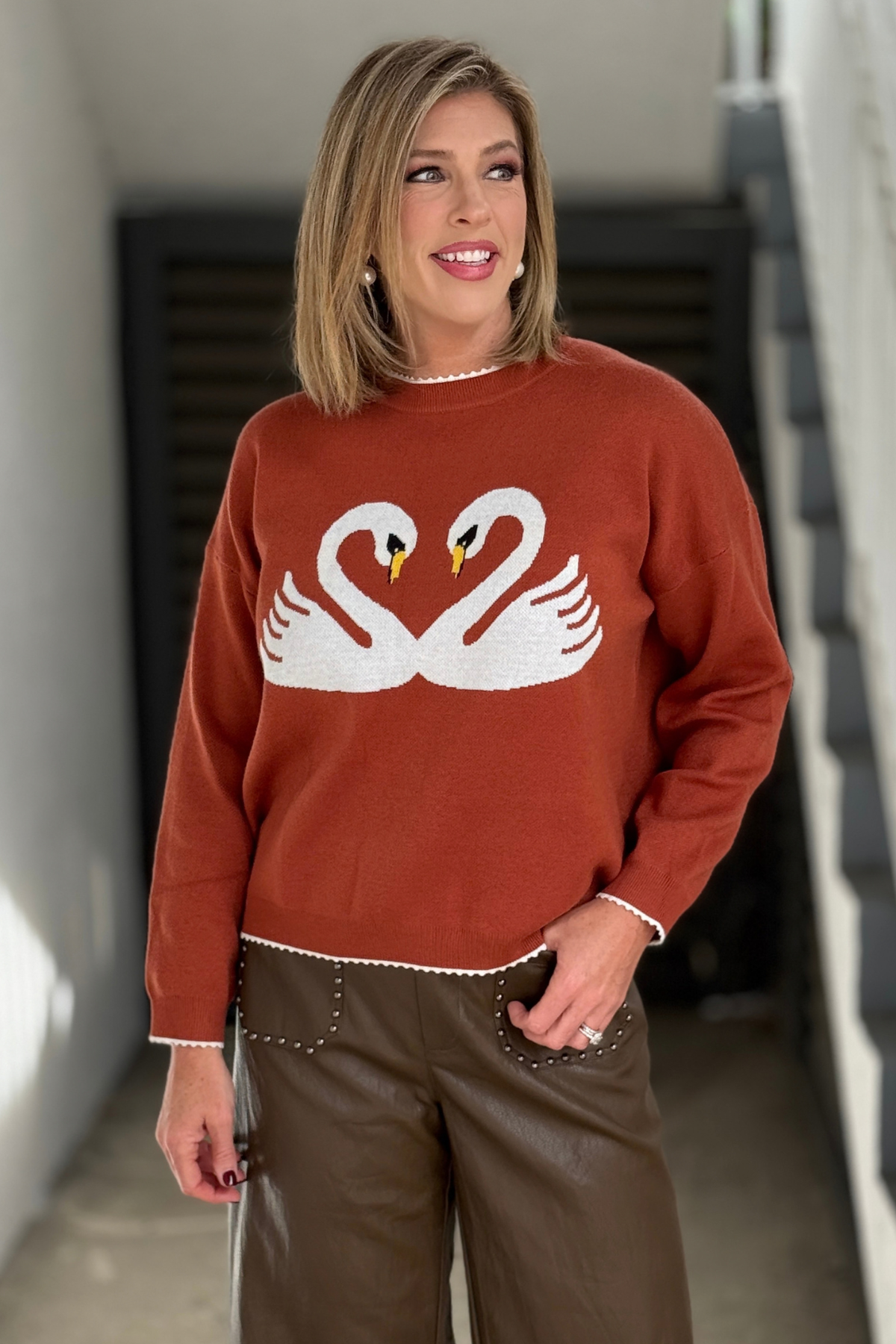 Rust fall sweater with two white swans forming a heart  