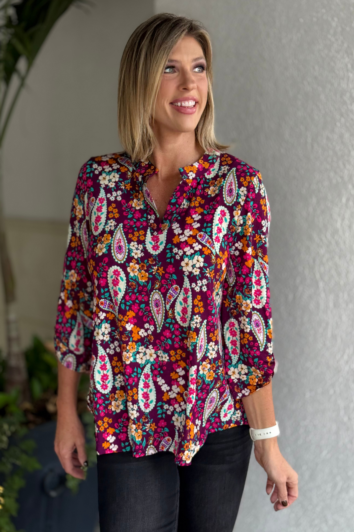 Woman wearing the TPN Berry Blossom Paisley Lizzy Top with rich berry background and colorful floral paisley print.