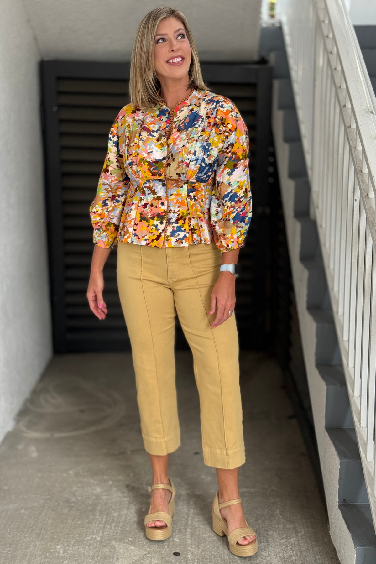 Woman wearing TRU LUXE Front Crease Stitch Crop Jeans in Tan with a colorful printed blouse and platform sandals.